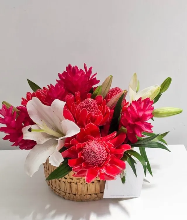 a beautiful red tropical flower arrangement in a rattan box.