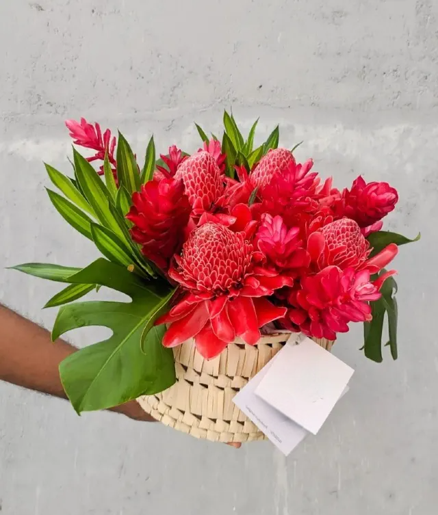 beautiful red tropical flower arrangement in a rattan box.