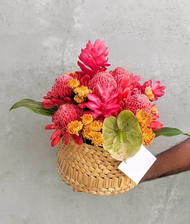 beautiful red tropical flower arrangement in a rattan box.
