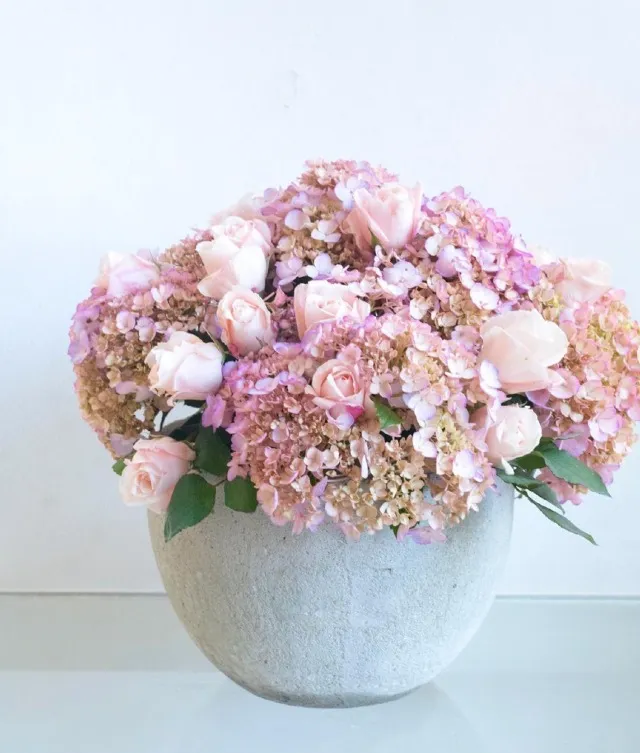 Gift your loved one a pink roses and hydrangea flower arrangement in a cement pot