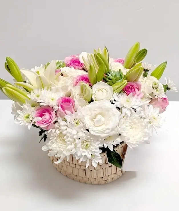 an enchanting arrangement of lilies, roses, and chrysanthemums nestled in a charming rattan box.