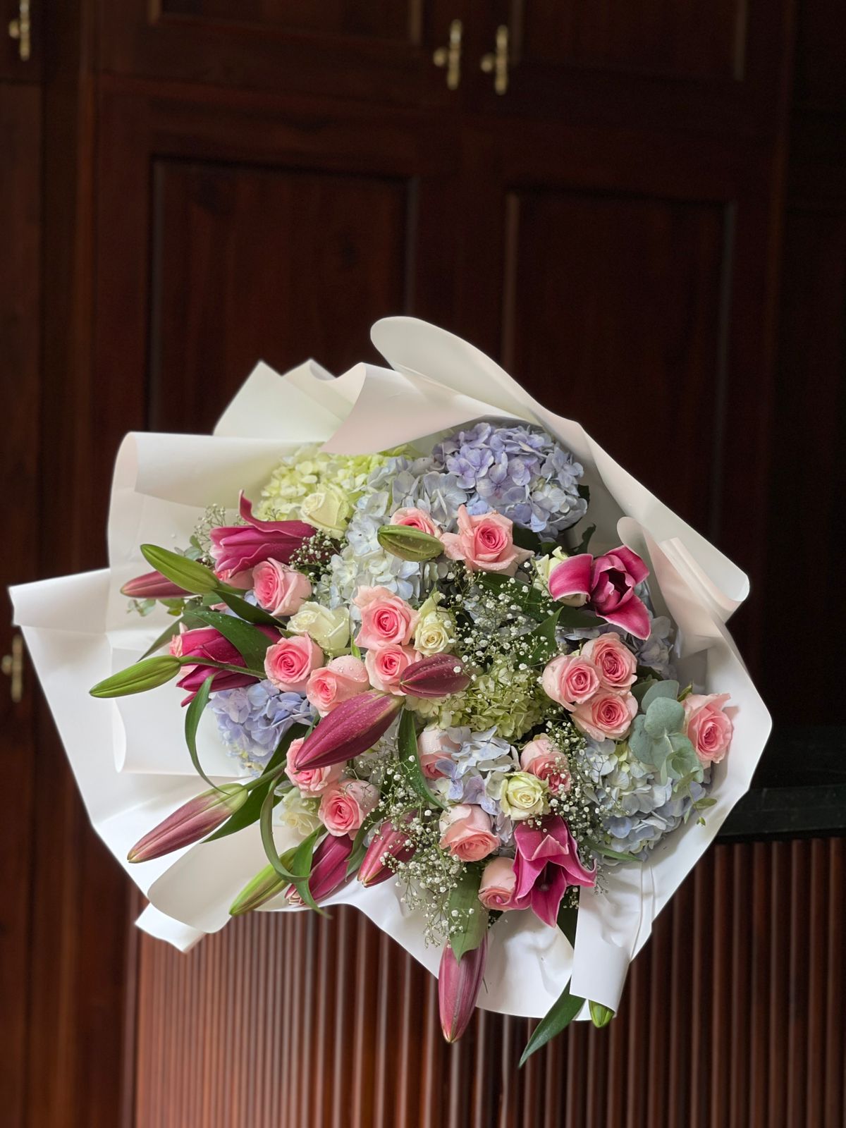Surprise your loved ones with a gorgeous bouquet featuring white roses, blush pink roses, lilies, and hydrangeas, all elegantly wrapped in ivory. A classic and heartfelt gesture, meticulously arranged to uplift their spirits and fill their hearts with warmth