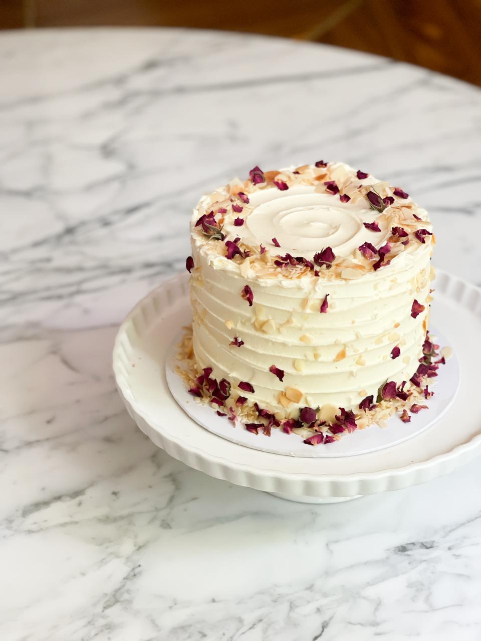 Enjoy a delightful 1.2kg Ribbon Almond Cake, adorned with toasted almonds and delicate rose petals—a perfect blend of flavor and elegance The cake has dimensions of 6 inches in diameter and 4-5 inches in height