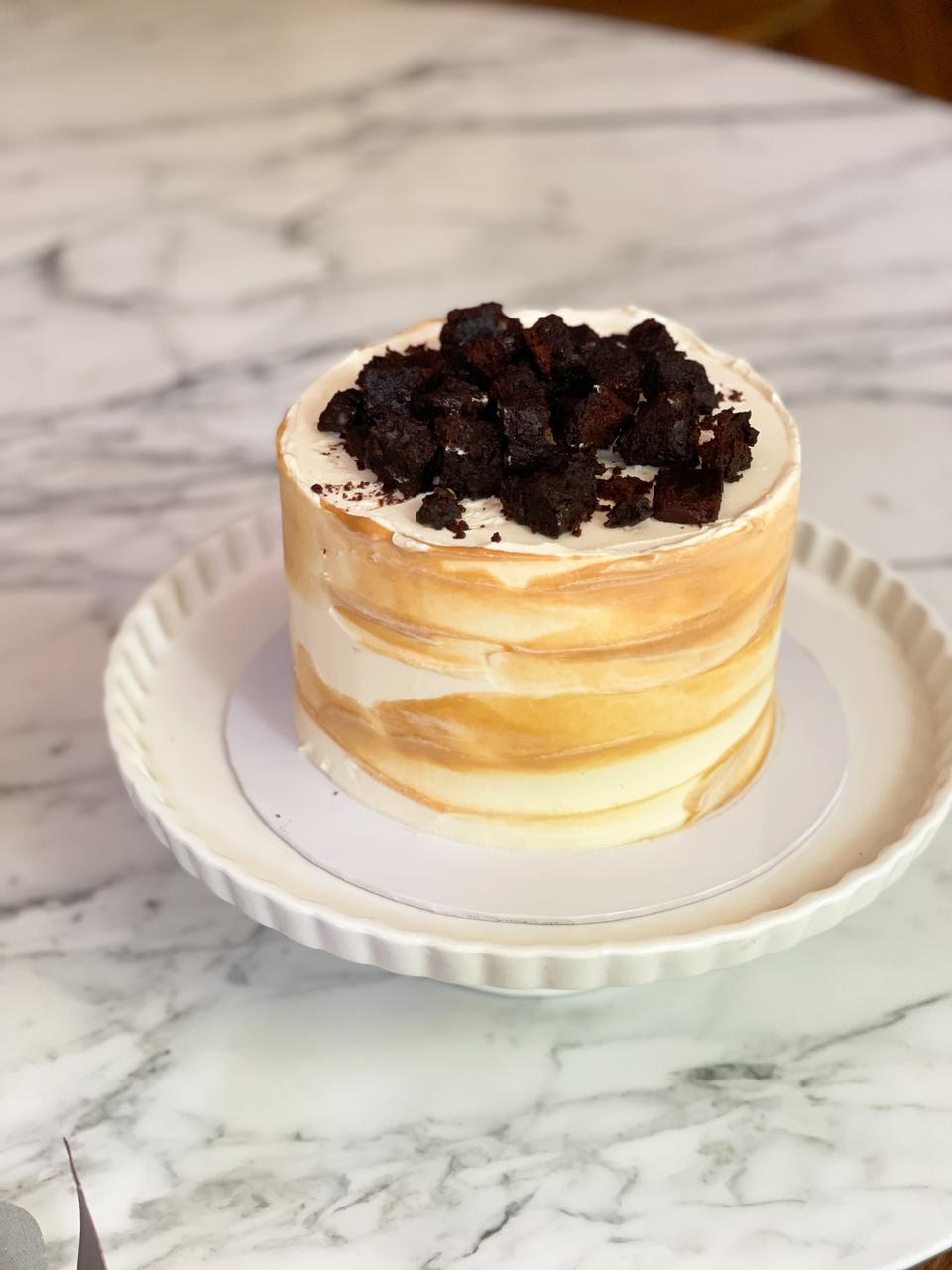 Indulge in a decadent 1.3kg Vanilla Salted Caramel Cake, featuring rich layers of caramel and fudgy bits for the perfect balance of sweetness and indulgence The cake has dimensions of 6 inches in diameter and 4-5 inches in height