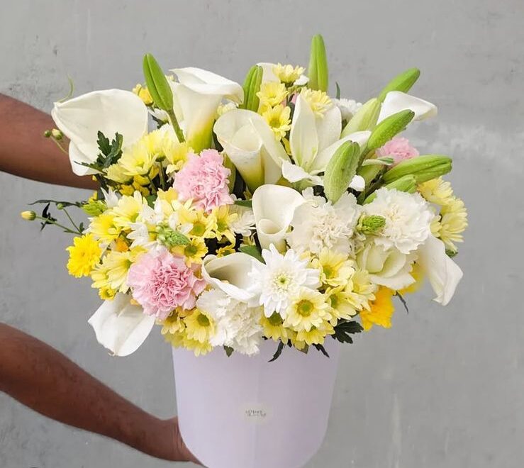 A graceful white basket filled with the elegance of lilies, soft chrysanthemums, and delicate roses.