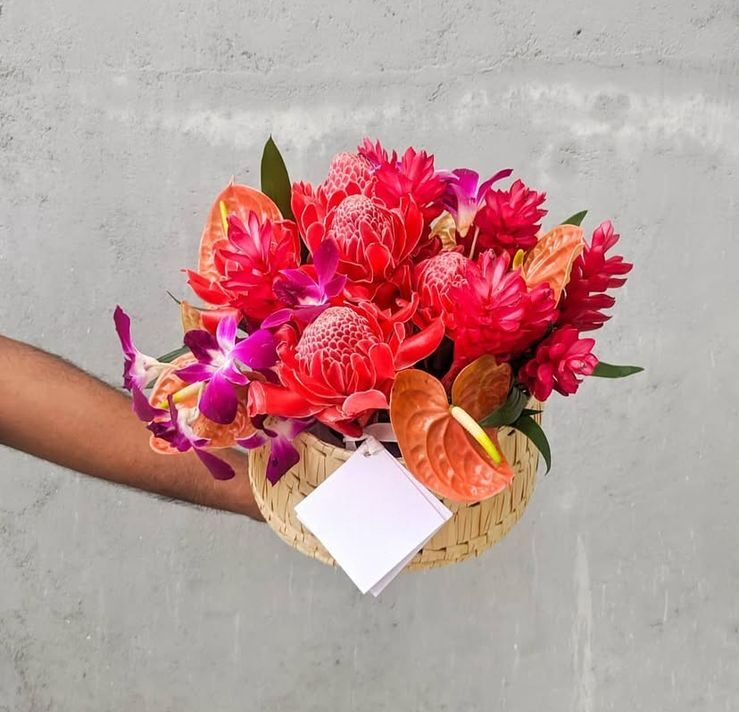 A stunning tropical arrangement in a charming cane basket, featuring vibrant tropical flowers and exotic anthuriums.