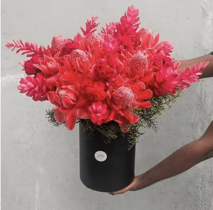 a stunning tropical flower arrangement in a sleek black basket.