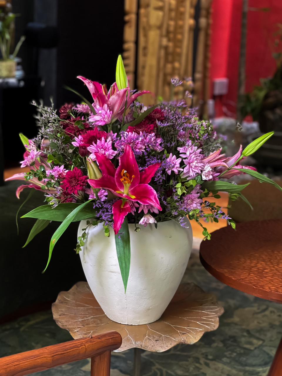 Gift a stunning arrangement of pink lilies, soft pink, dark pink, and red chrysanthemums, complemented by lush foliage and beautifully presented in a beige vase. A perfect blend of charm and sophistication for any occasion.